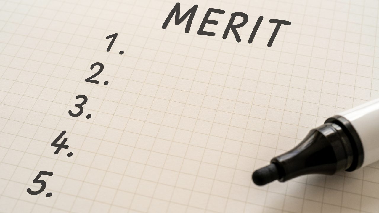 meritと数字が書かれたノートとペン