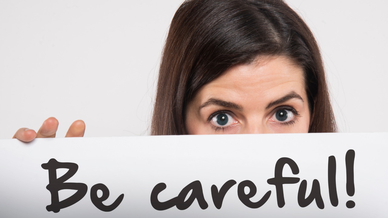 Be careful!の紙を持った女性